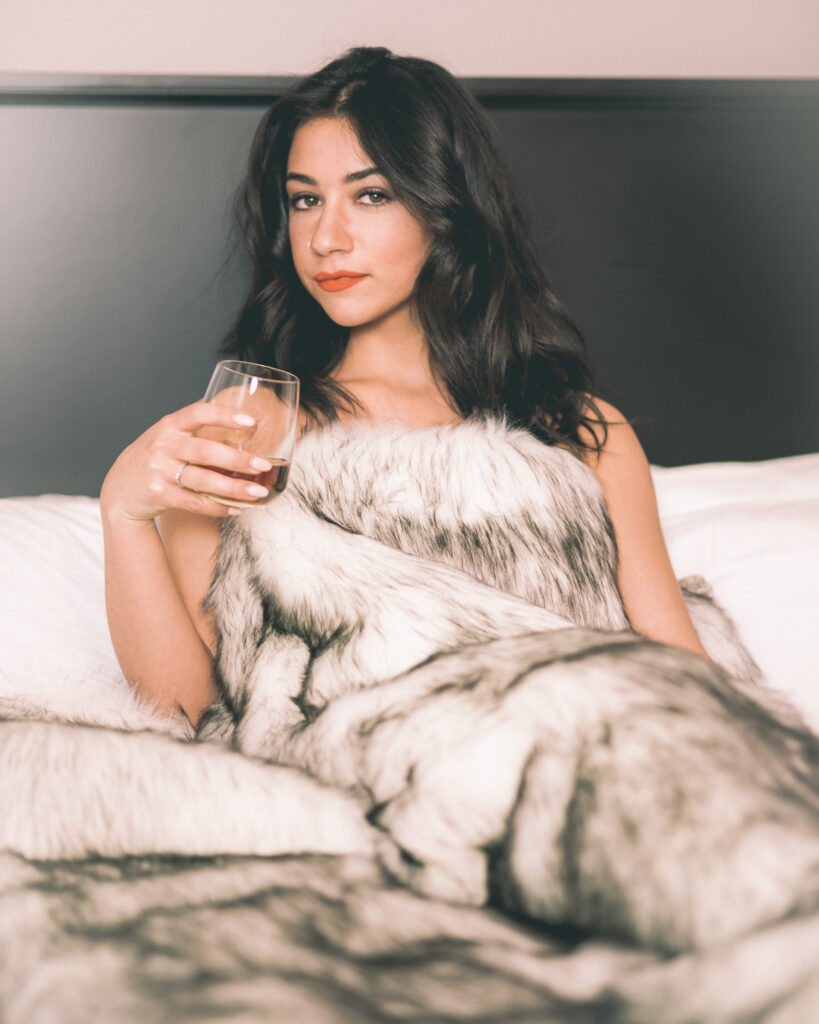 boudoir portrait of a dark haired woman wrapped in a fur blanket