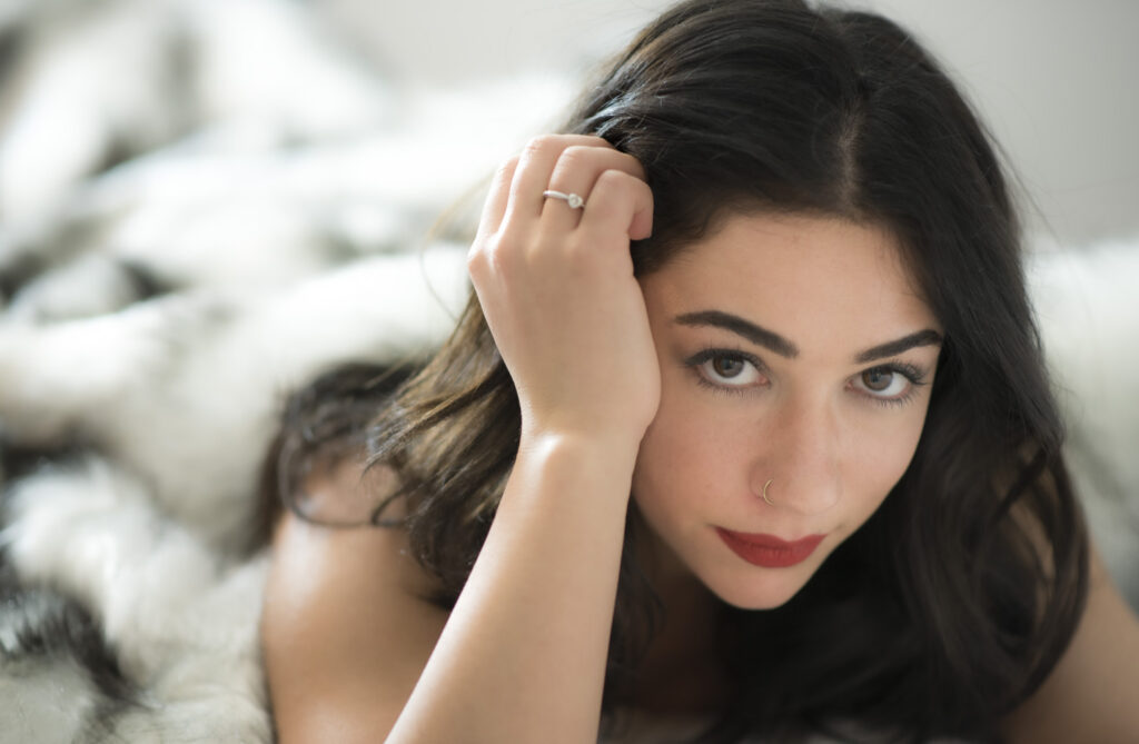 boudoir portrait of a black haired woman wrapped in a fur blanket